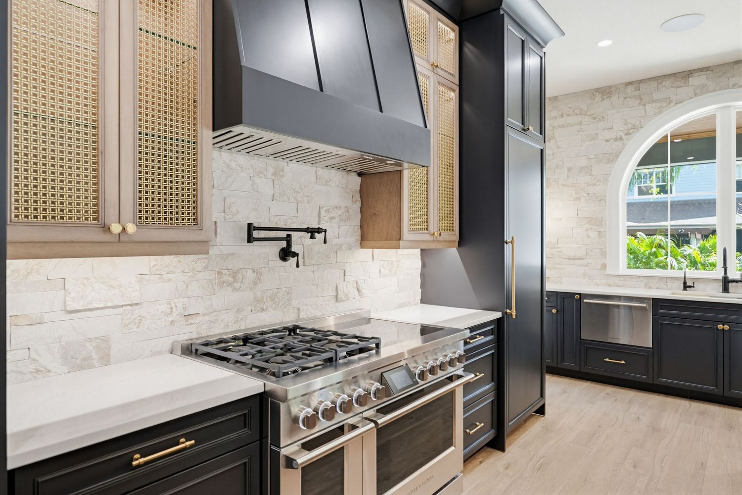 Modern kitchen design with black cabinets, gold hardware, marble backsplash and custom wood lattice details.