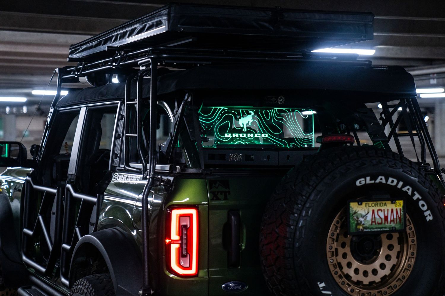 Dark parking garage interior showing modified off-road vehicles with custom lighting.