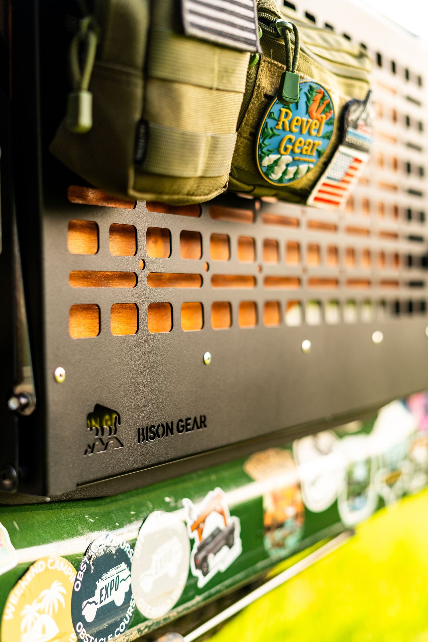 Close-up of tactical gear mounted on orange MOLLE panel with stickers.