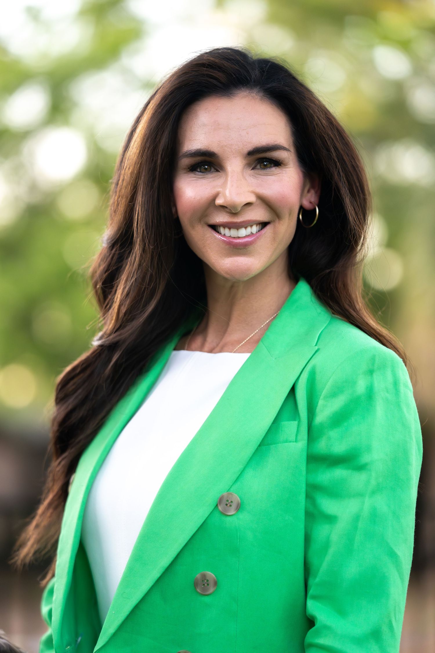 Professional portrait series showing a bright kelly green blazer with white top against a soft natural outdoor background.