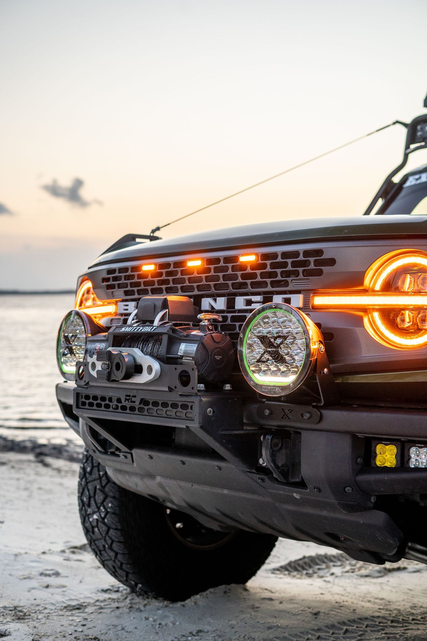 Close-up view of a Ford Bronco's front grille and LED lighting system at sunset.