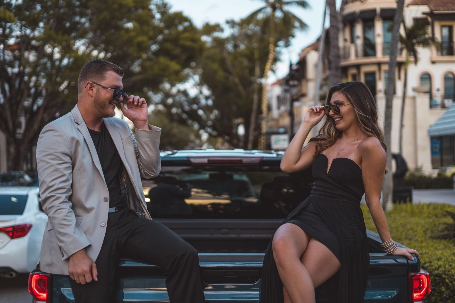 Casual couple's photoshoot near parked cars during golden hour.