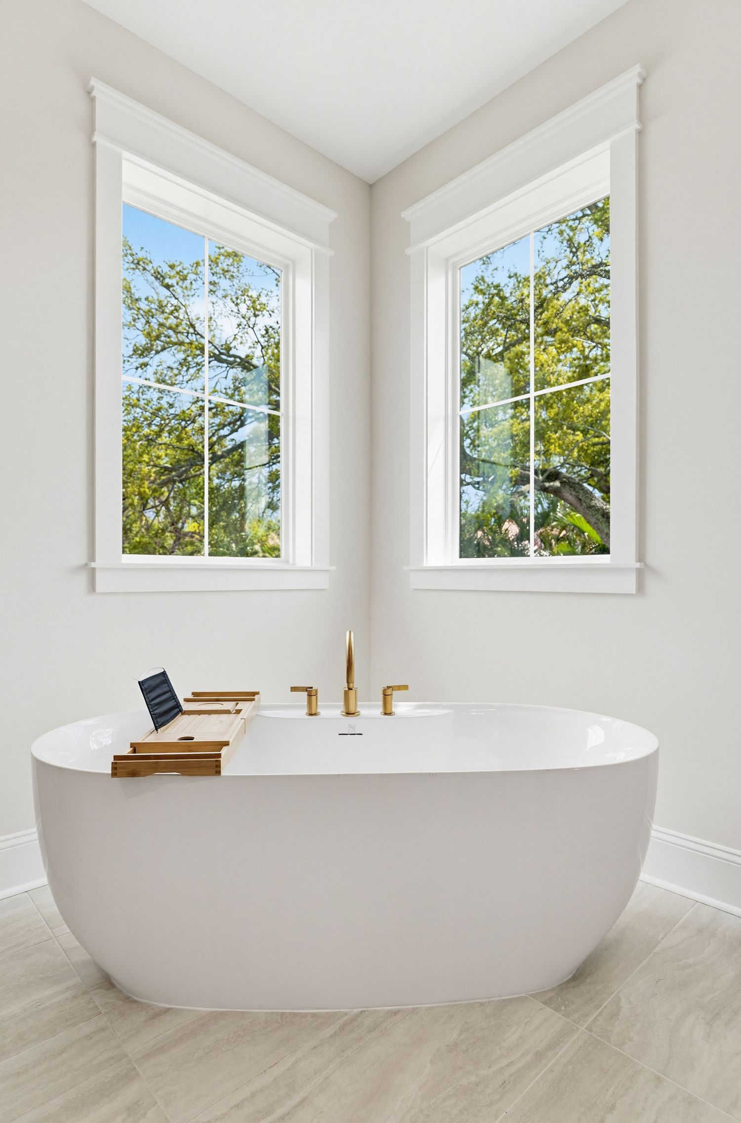 Modern freestanding white bathtub in bright bathroom with multiple windows and natural light streaming in.