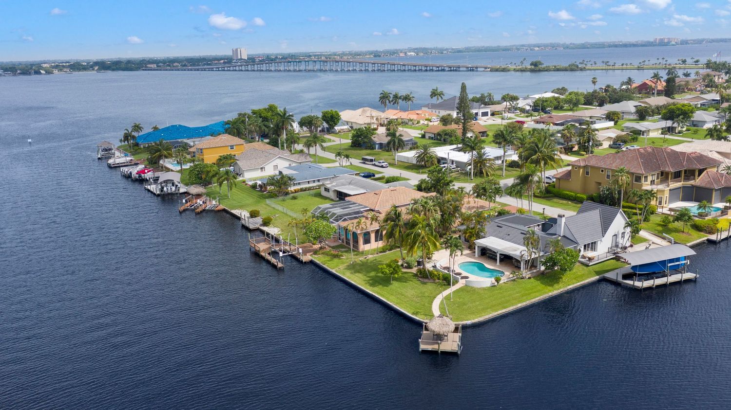 Aerial panoramic view of waterfront homes with private docks along Florida's coastal waterway on a sunny day.