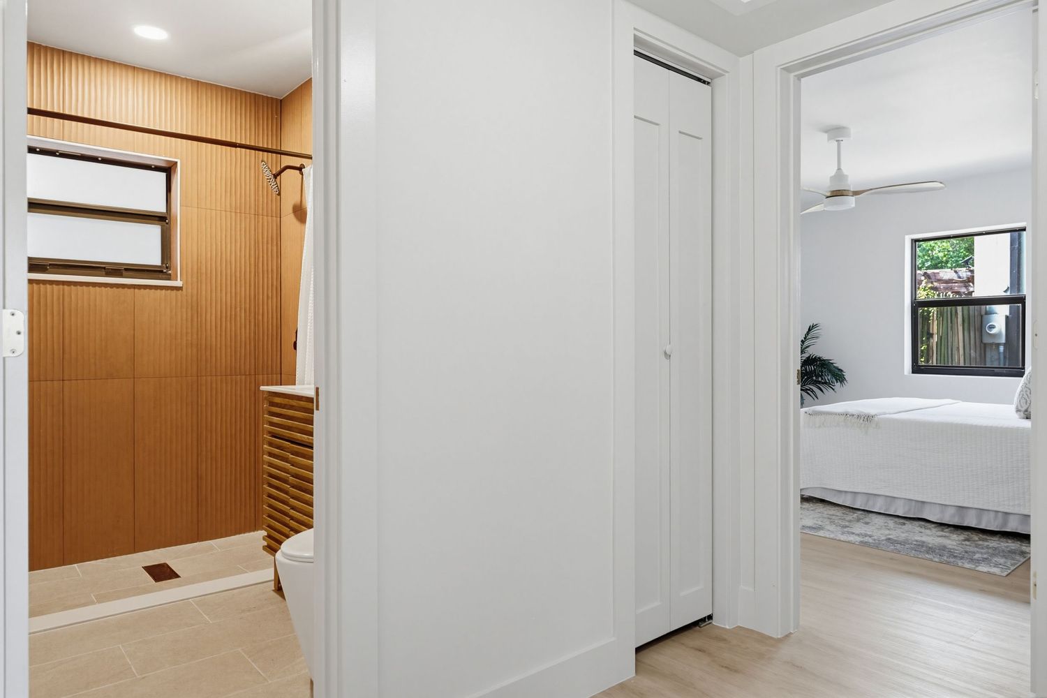 Modern white interior hallway with recessed lighting and wooden accent walls features sleek minimalist design elements.