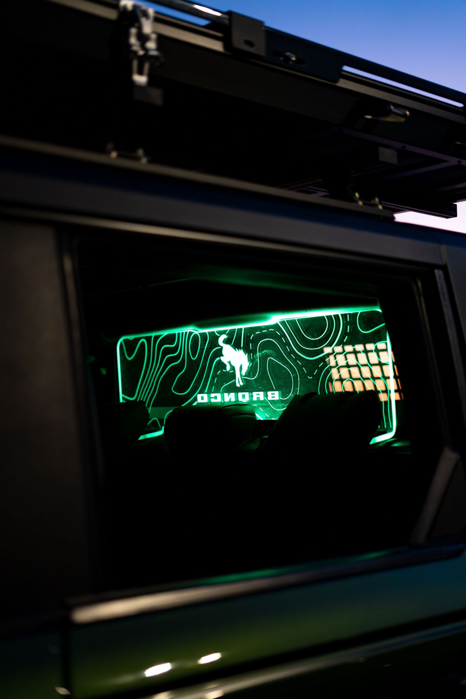 Illuminated green neon design visible through vehicle window at night.