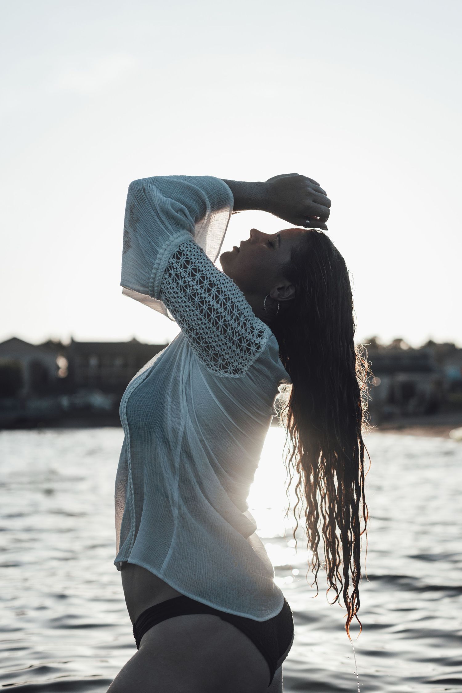 Artistic beach portraits with wet hair and white shirt against ocean backdrop.