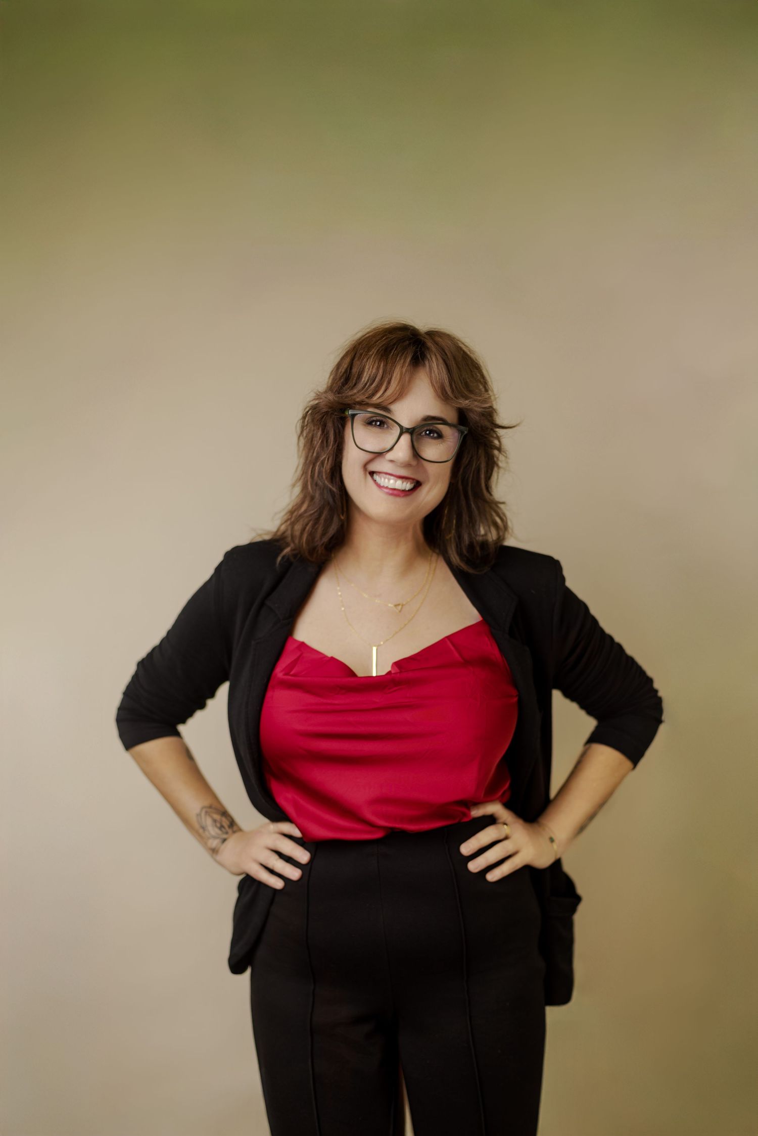 Professional portrait series showing figure in red top and black cardigan against neutral background.