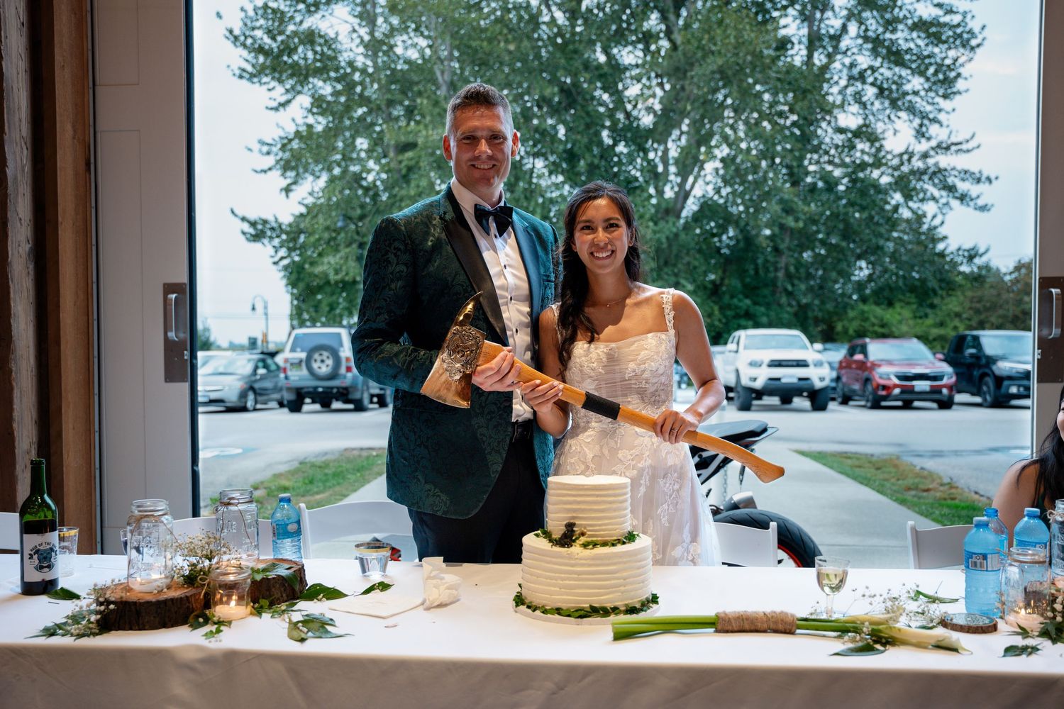 Bride and groom cutting their white wedding cake together at reception venue.