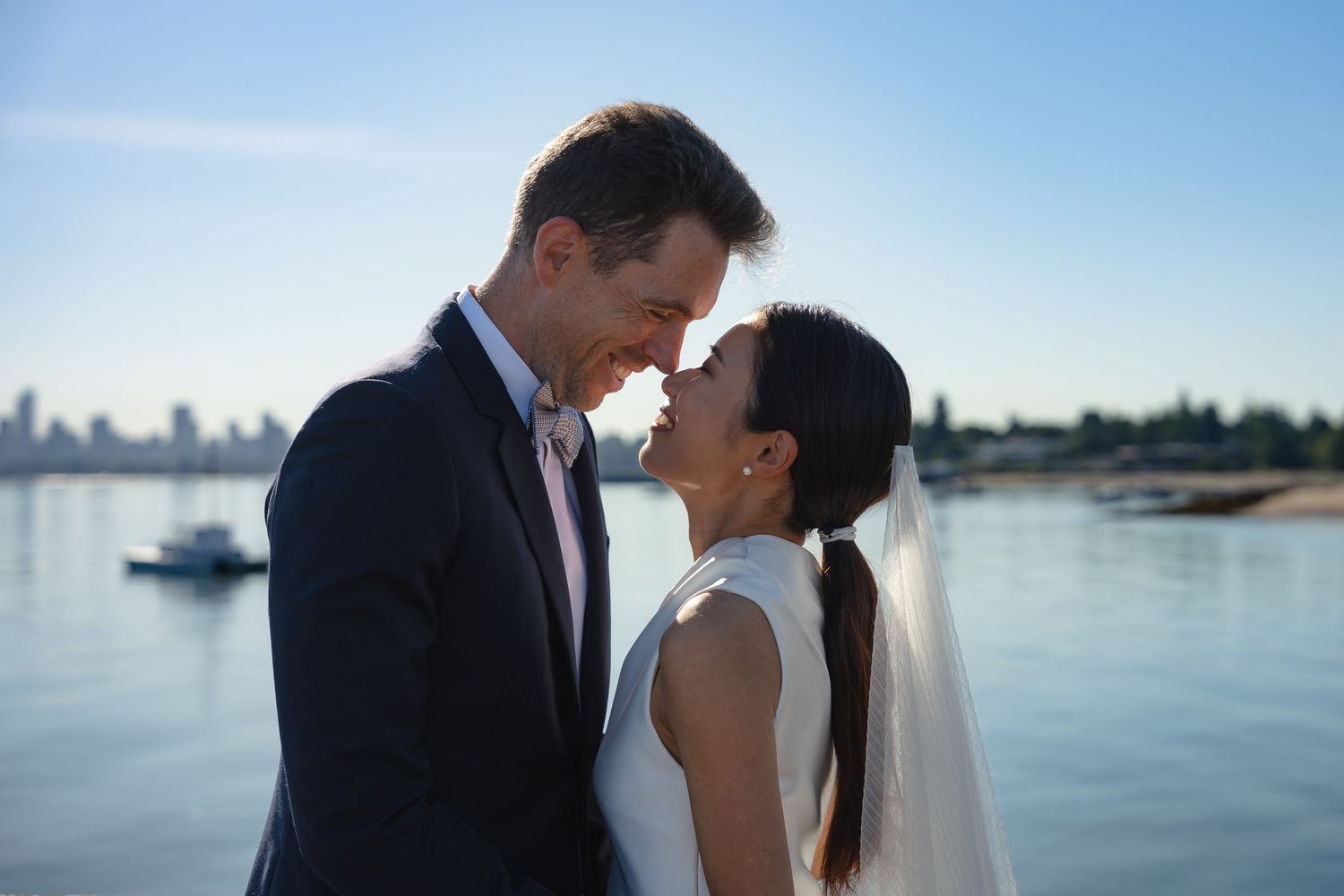 Bride and groom sharing a romantic moment near waterfront on their wedding day.