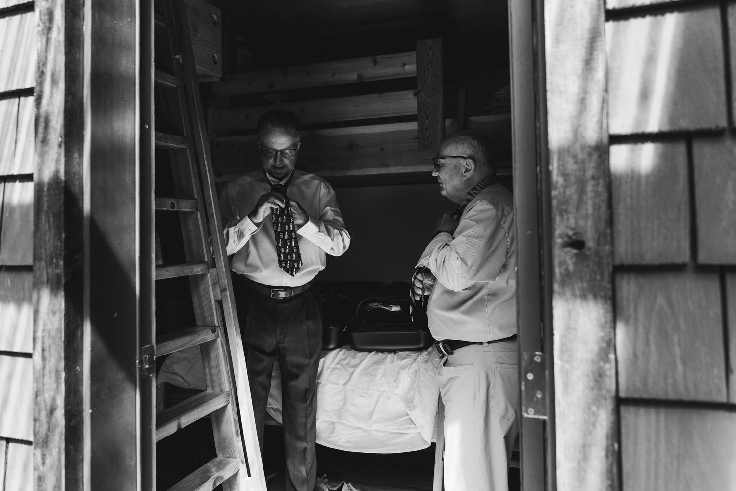 Two men in formal attire stand in a wooden doorway in a vintage black and white photograph.