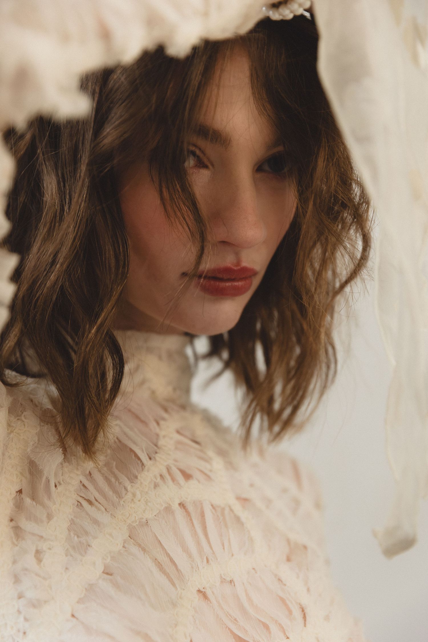 A series of artistic portraits showing a person in a delicate white ruffled Victorian-style high collar blouse.