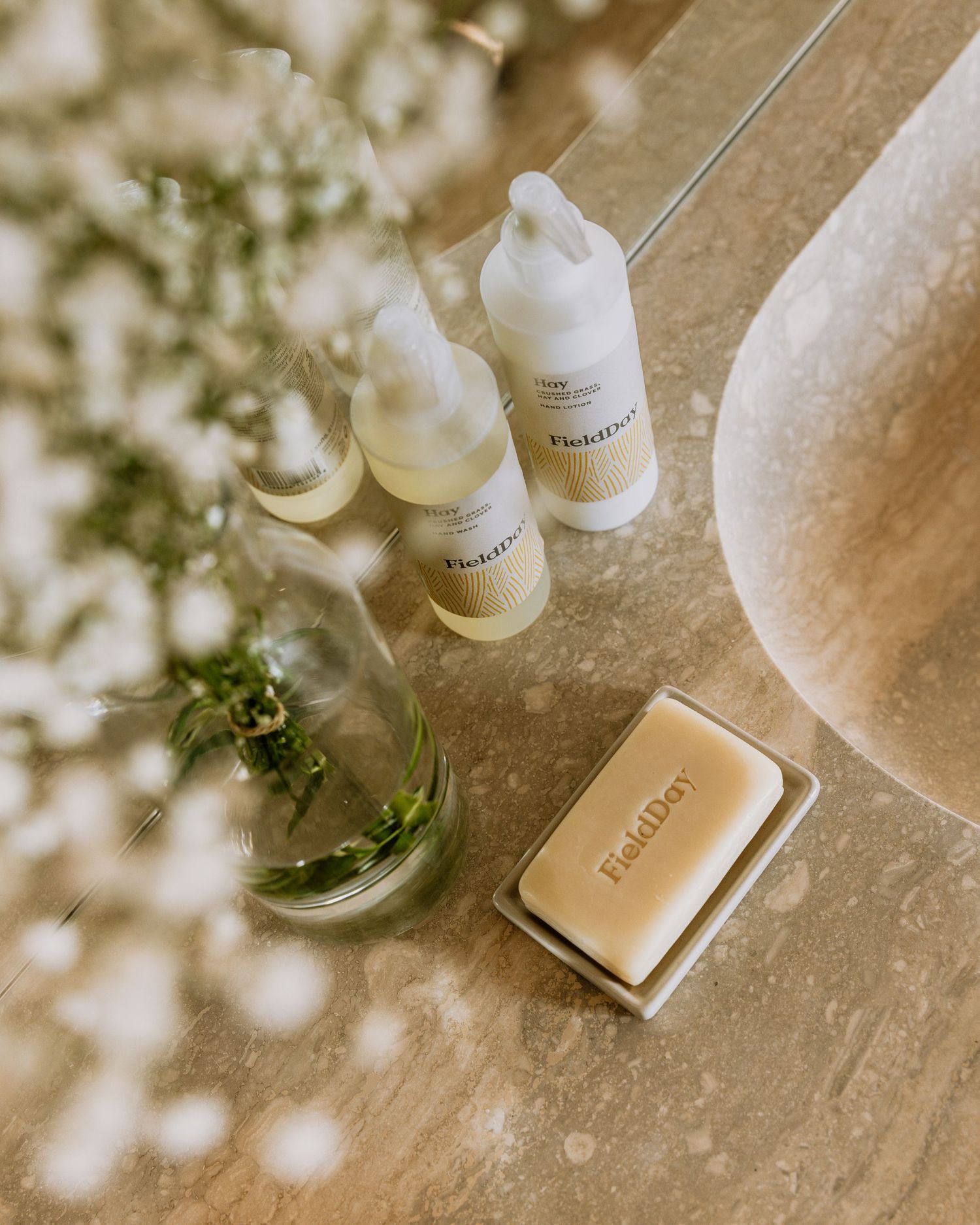 Elegant skincare and beauty products arranged on a textured beige surface with soft floral accents and shadows.