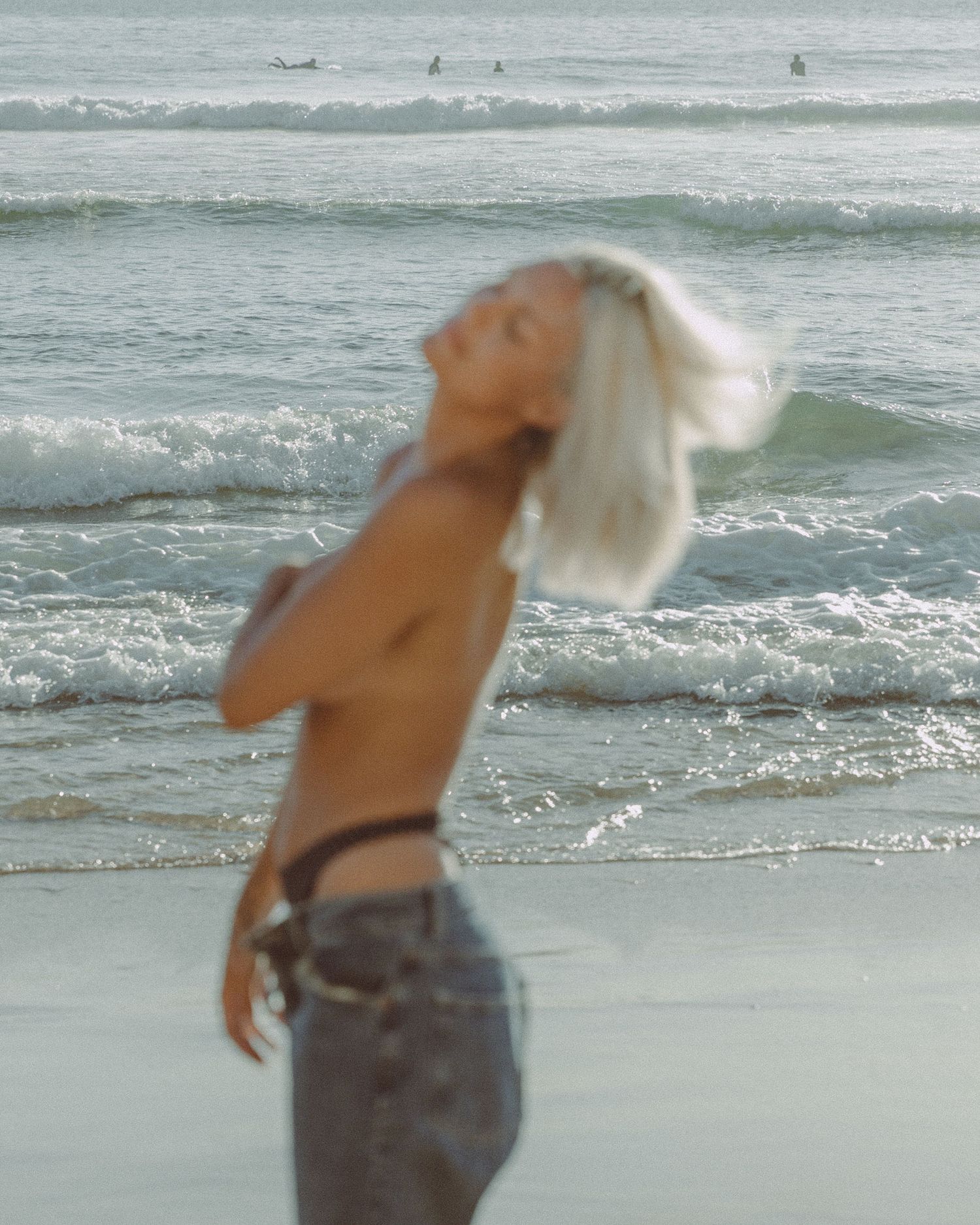 Dreamy beach scene with waves and movement captured in soft, ethereal light.