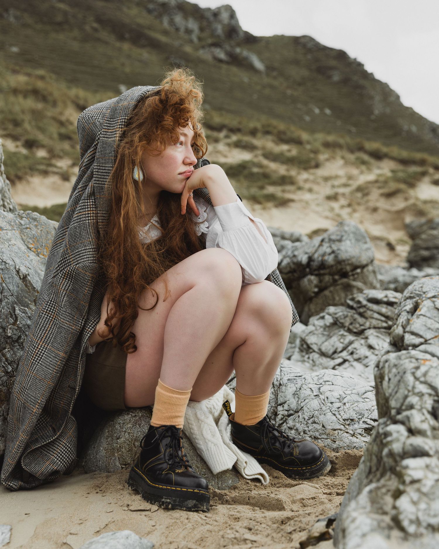 Moody coastal editorial style photography with rocks and gray wool blanket on beach shot in Donegal, Ireland.