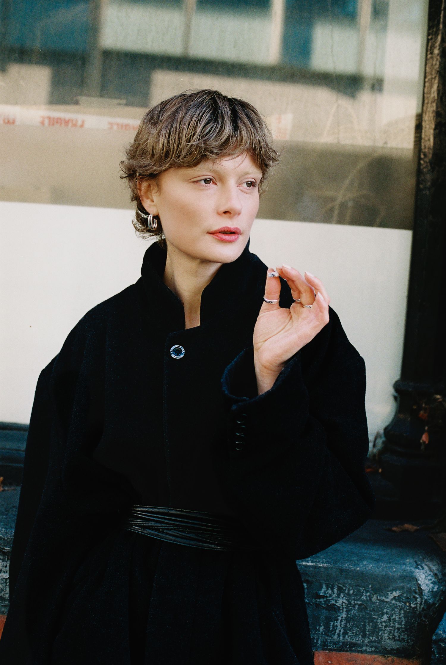 Fashion portrait triptych showing model in black coat against urban backdrop with dramatic lighting and composition.