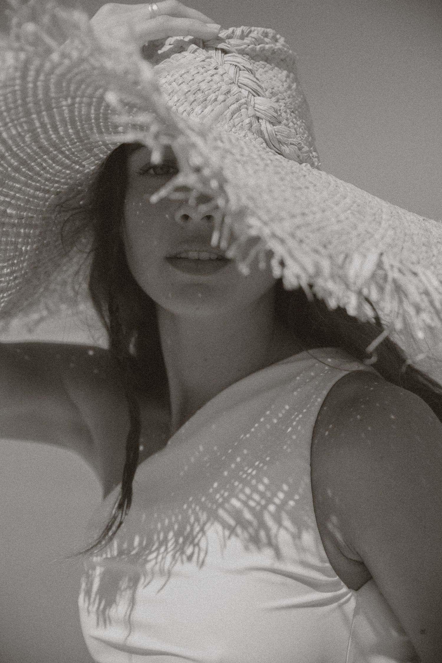 A series of black and white photos showing someone wearing a delicate white lace hat casting shadows on their face.
