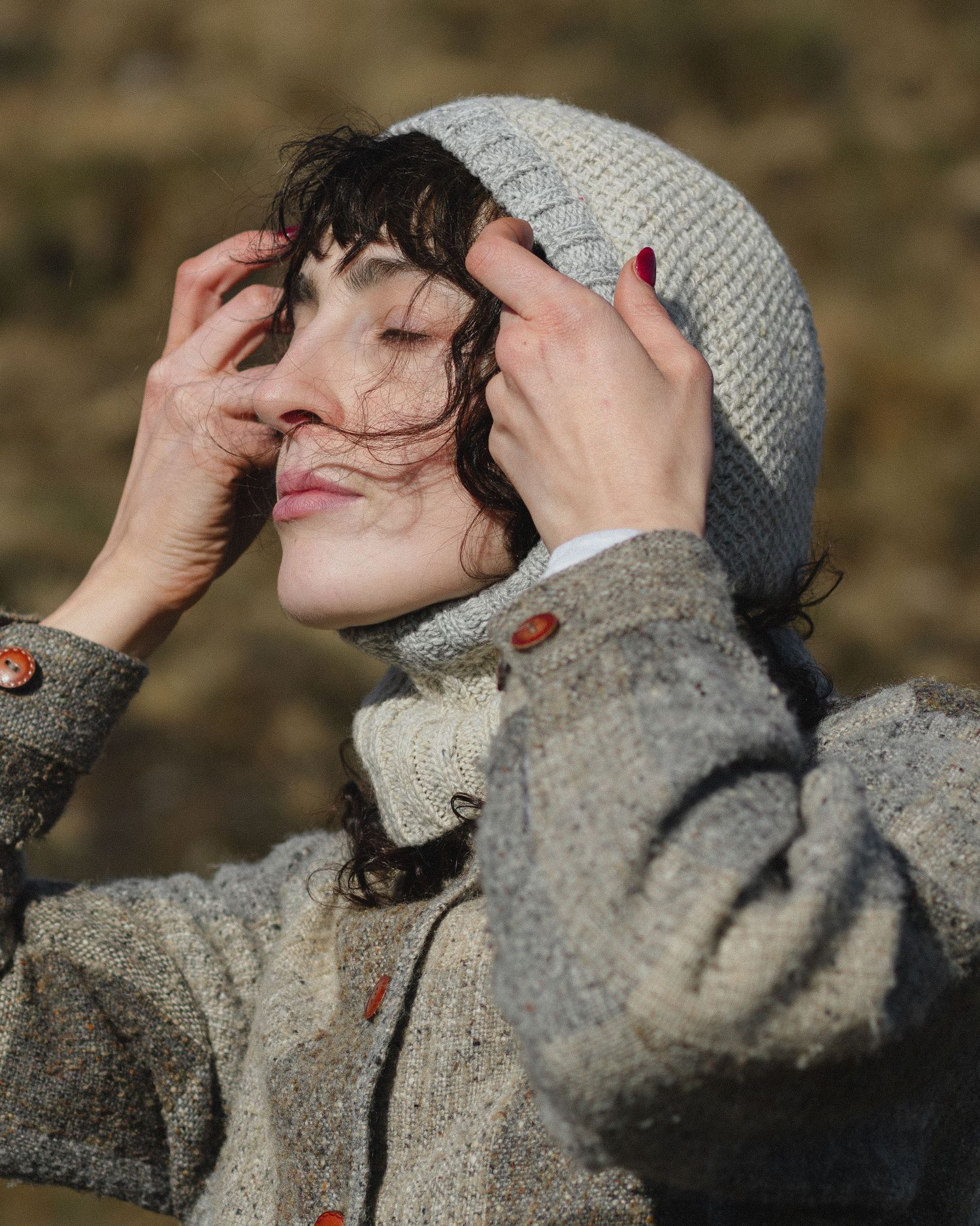 Person wearing a gray knit beanie and sweater poses playfully in a series of candid outdoor shots.