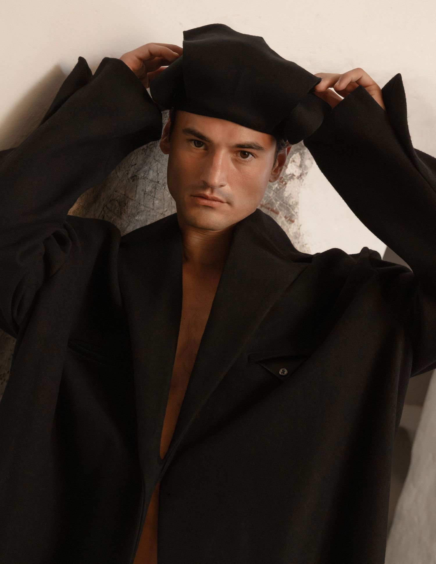 A series of black and white studio portraits showing someone wearing an oversized black blazer against a light background.