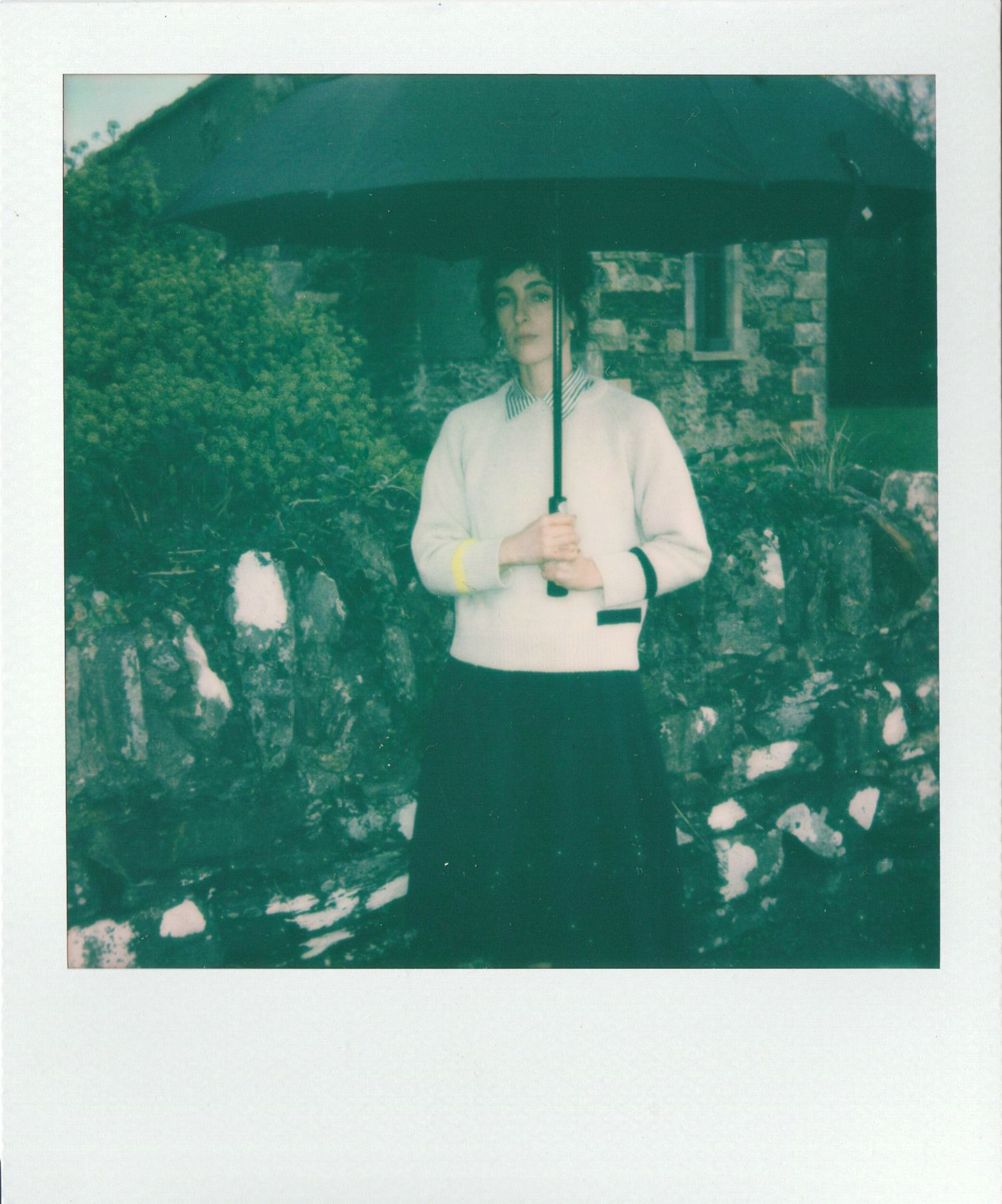 Vintage green-tinted photograph showing a person in white clothing standing in a garden setting.