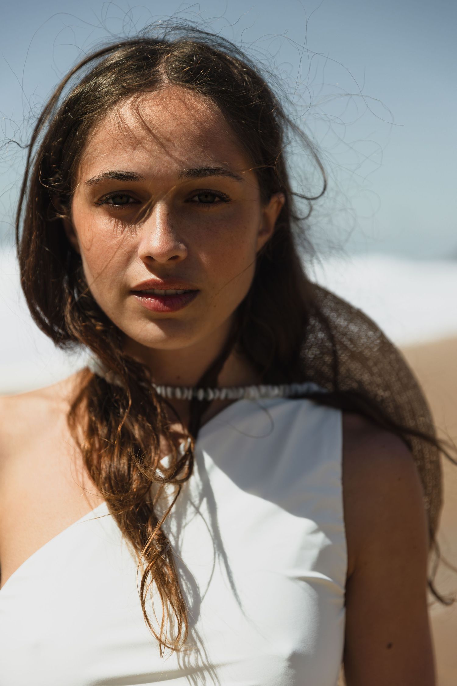 A series of close-up portraits showing a woman with windswept dark hair against a bright sky background.
