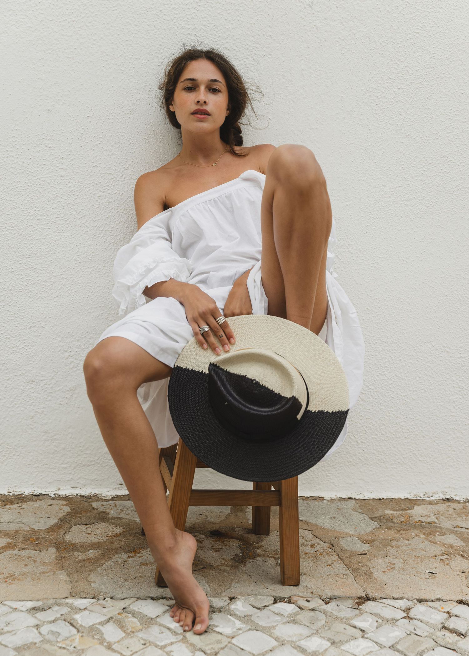 Minimalist editorial white wall photoshoot featuring artistic poses on a wooden chair.