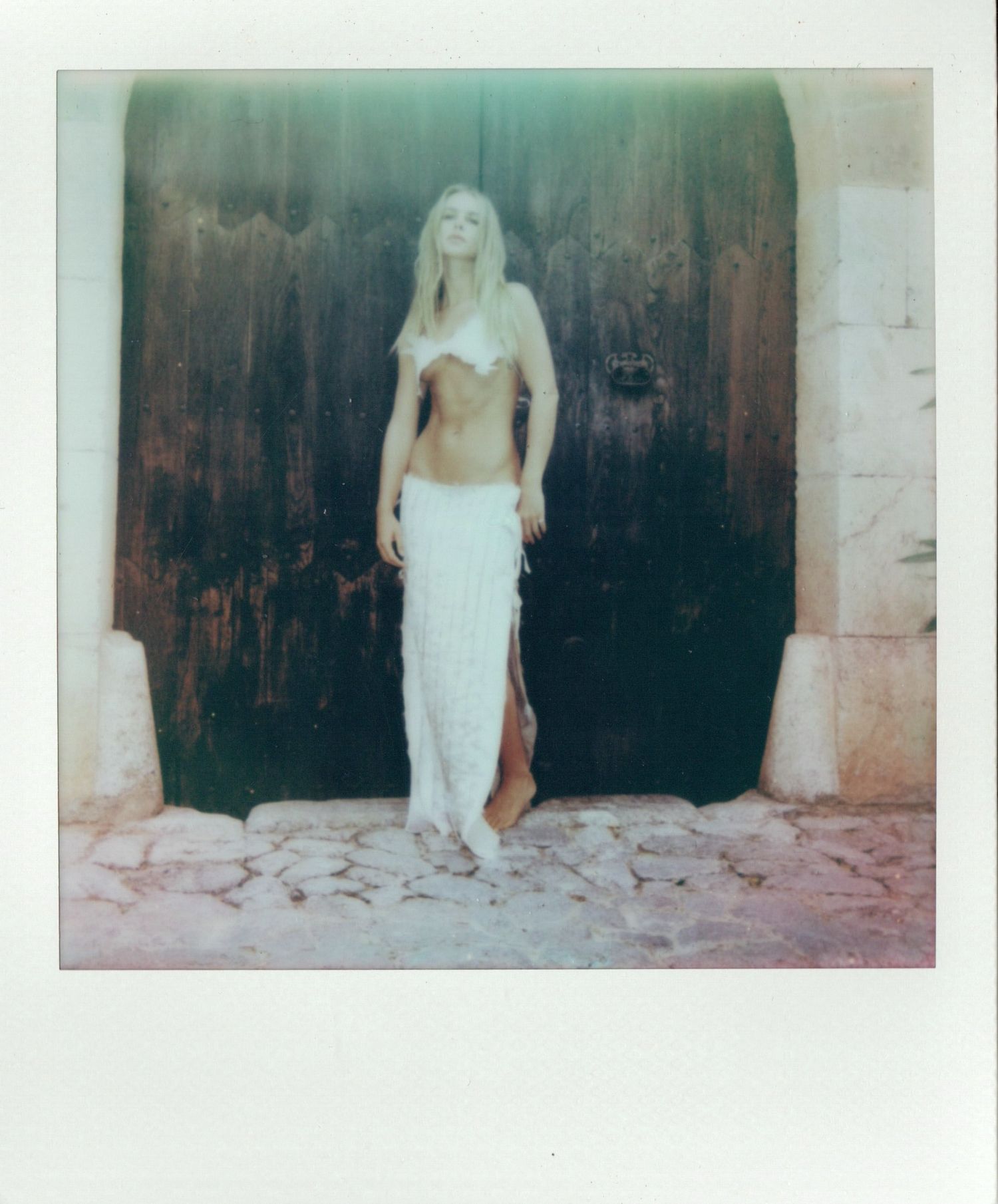 A figure in a white dress stands in front of a dark background in a series of vintage polaroid-style photographs.