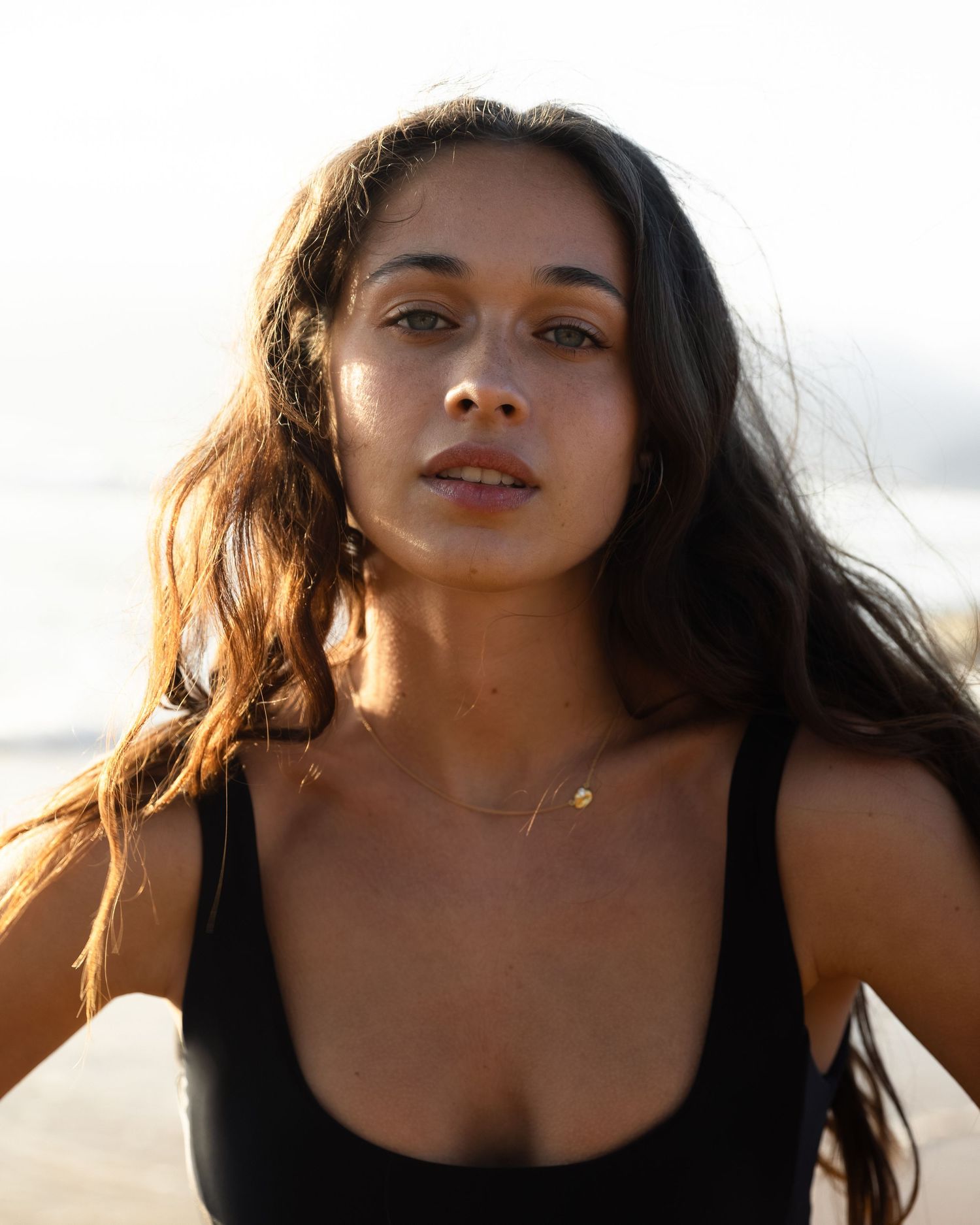 A woman with long dark hair poses outdoors in a sequence of closeup portraits at sunset.