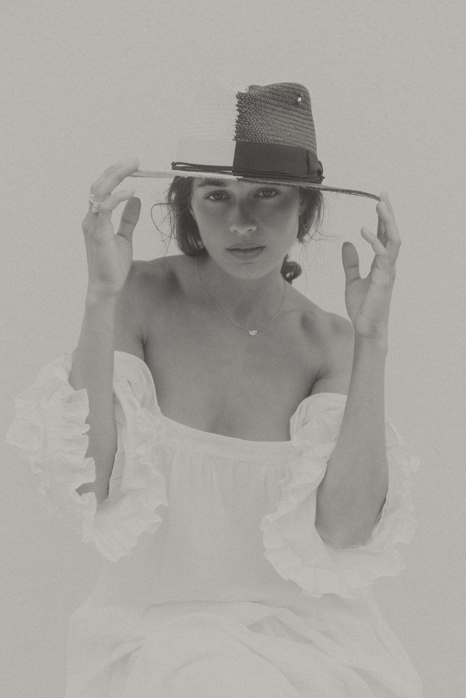 A series of four black and white vintage style photos showing a person in a sunhat and white dress against a light background.