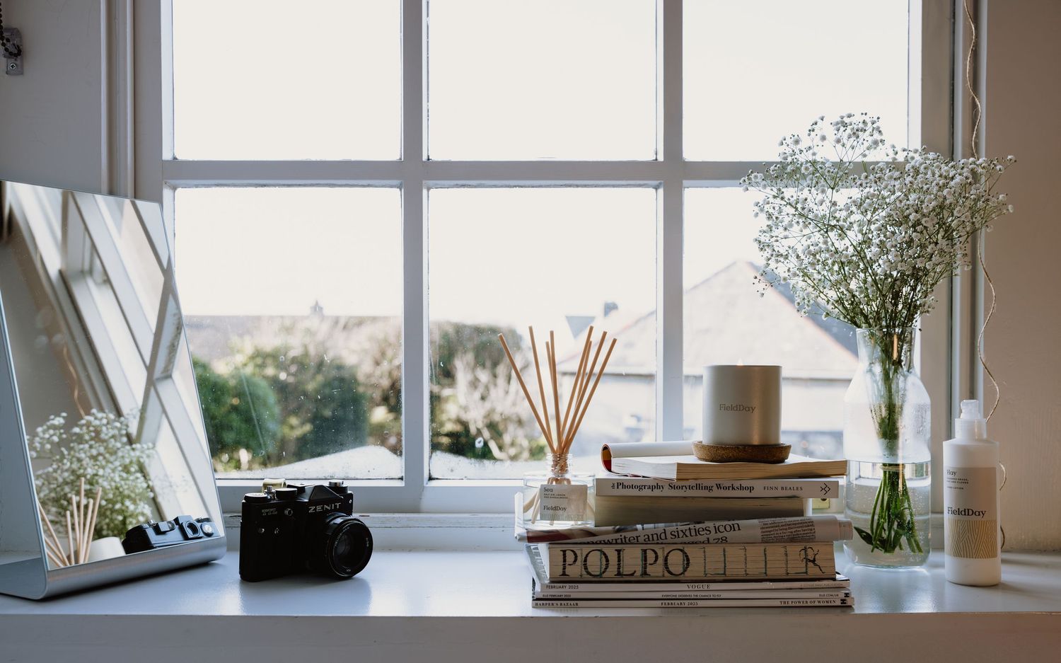 A series of window sills decorated with plants, books, and decorative objects in a bright interior space.