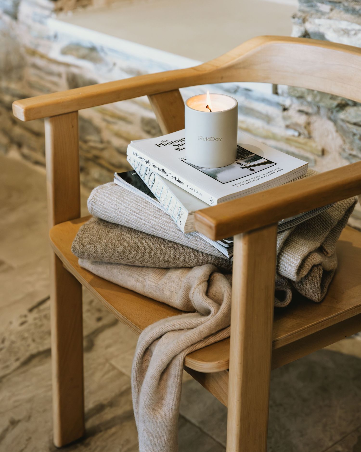 Wooden side table with white ceramic bowl and folded textiles displayed in a minimalist setting.