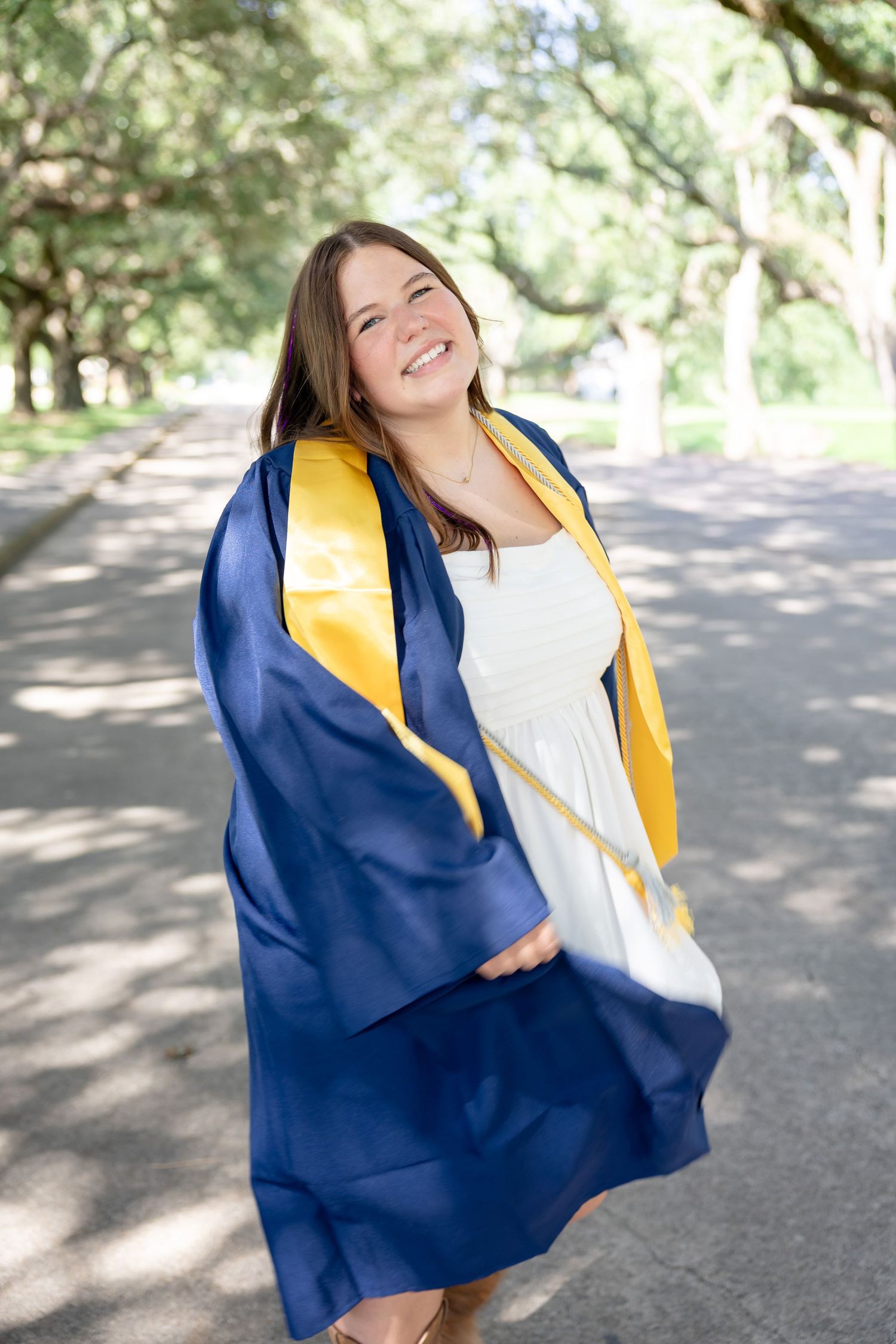 outdoor senior photography girl blue cap and gown twirling friendswood texas graduation