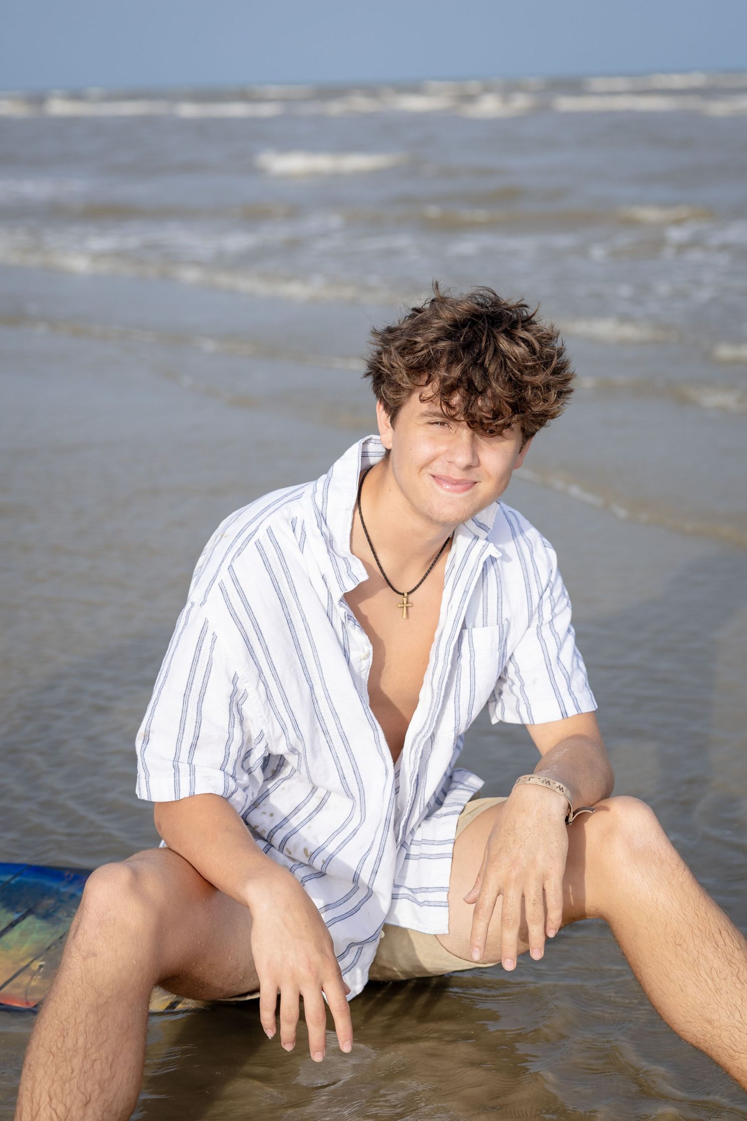 senior boy sitting in water sunset beach senior photo galveston high school senior