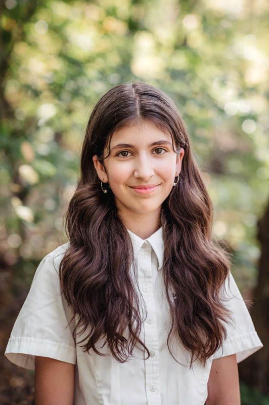 Student in white collared shirt poses for casual school portraits outdoors.
