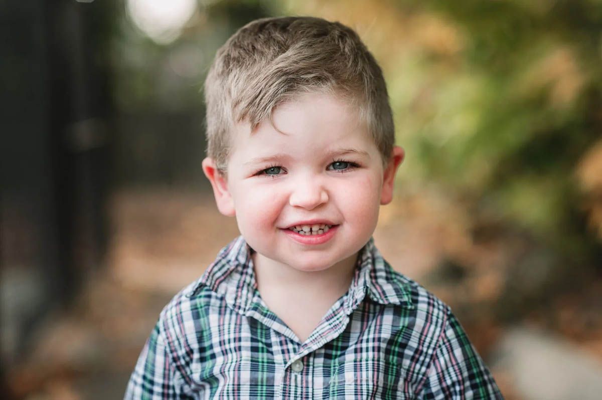 Three school portraits with plaid and black uniforms against a natural outdoor background.