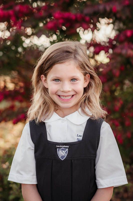 Student portrait series showing a child in white and navy school uniform with pink floral backdrop.
