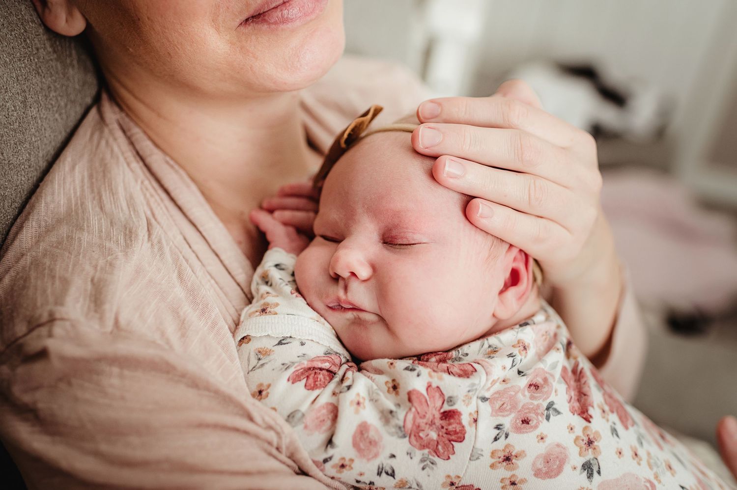 Peaceful sleeping baby in floral outfit resting against mother.