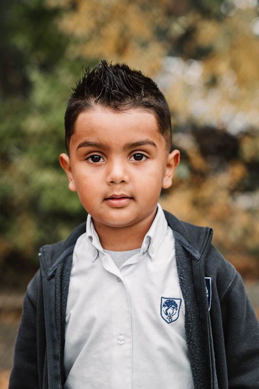 Student in a navy blazer and white collared shirt with school crest posing for a portrait.