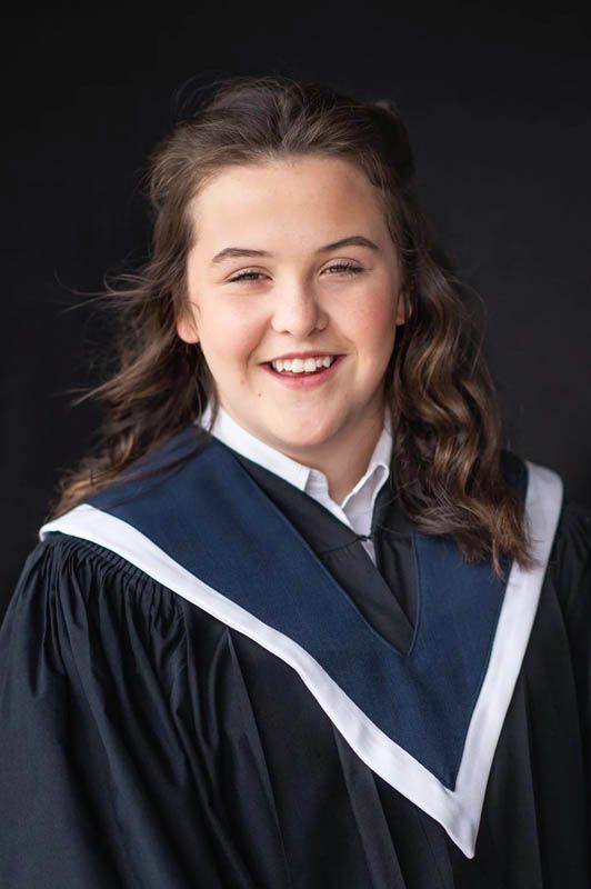 Professional graduation portraits show student in navy gown with white collar against dark background.