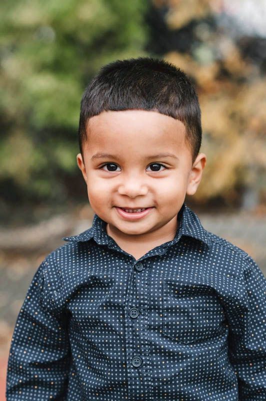 Outdoor portrait series showing a young child in a navy polka dot shirt with joyful expressions in natural lighting.