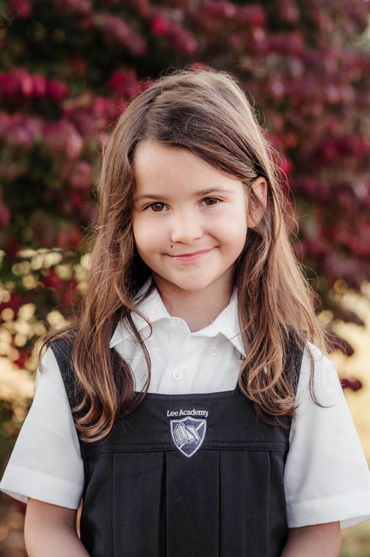 Student portraits taken outdoors showing uniforms with school crest against autumn foliage.