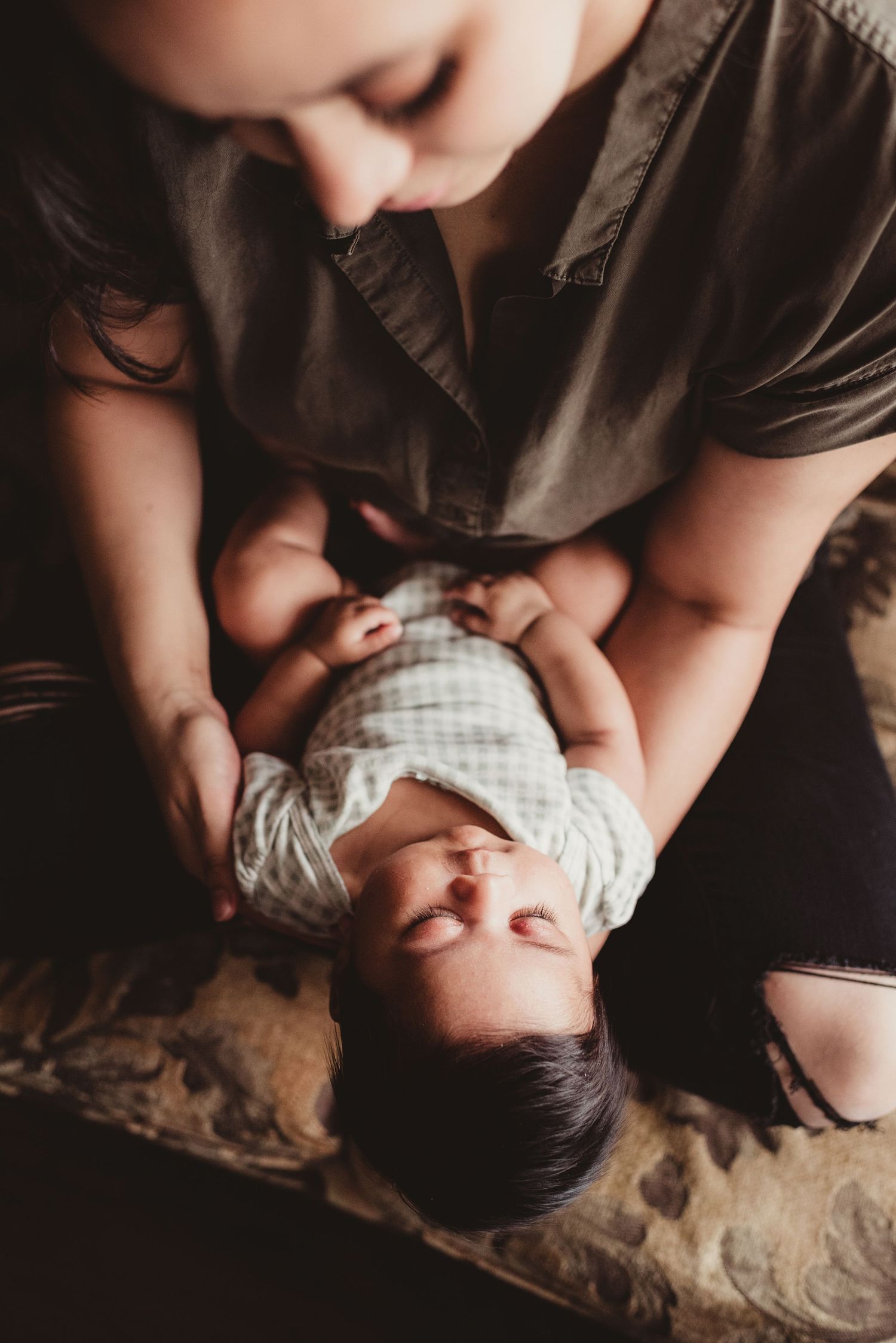 Overhead view of tender moment between mother and baby in soft natural lighting.
