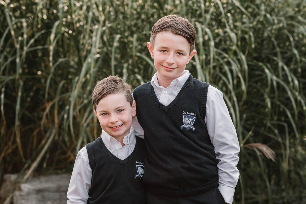 Students wearing school uniforms smile during an outdoor photo session.