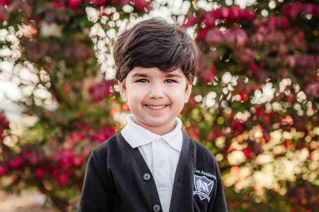 School portraits with bright pink and white flowers blooming in background.