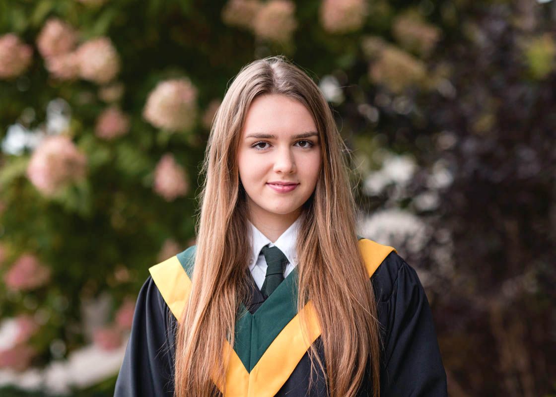 Graduation photos of students in black gowns with yellow sashes against natural backdrop.