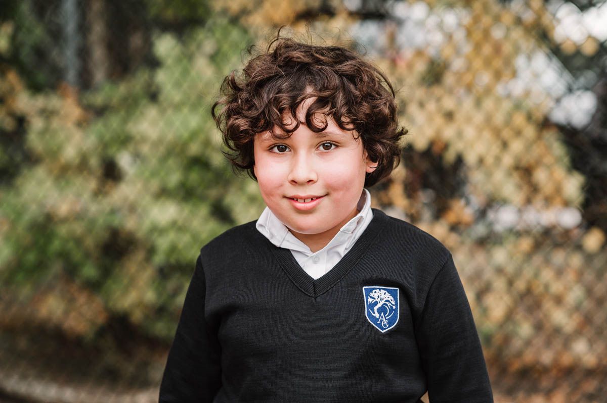 Student portraits showing various expressions while wearing a black school uniform with crest.