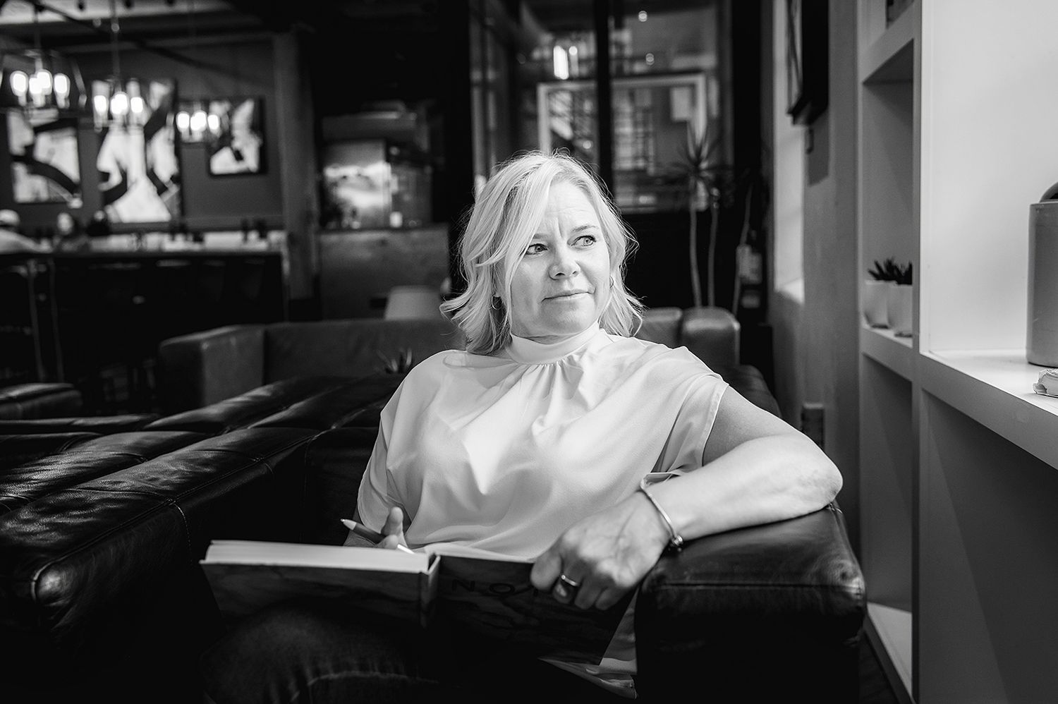 Black and white portrait of person seated by window in restaurant.
