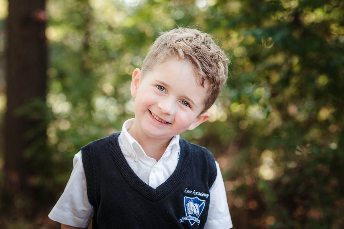 Students in school uniforms share joyful moments outdoors among autumn foliage and trees.
