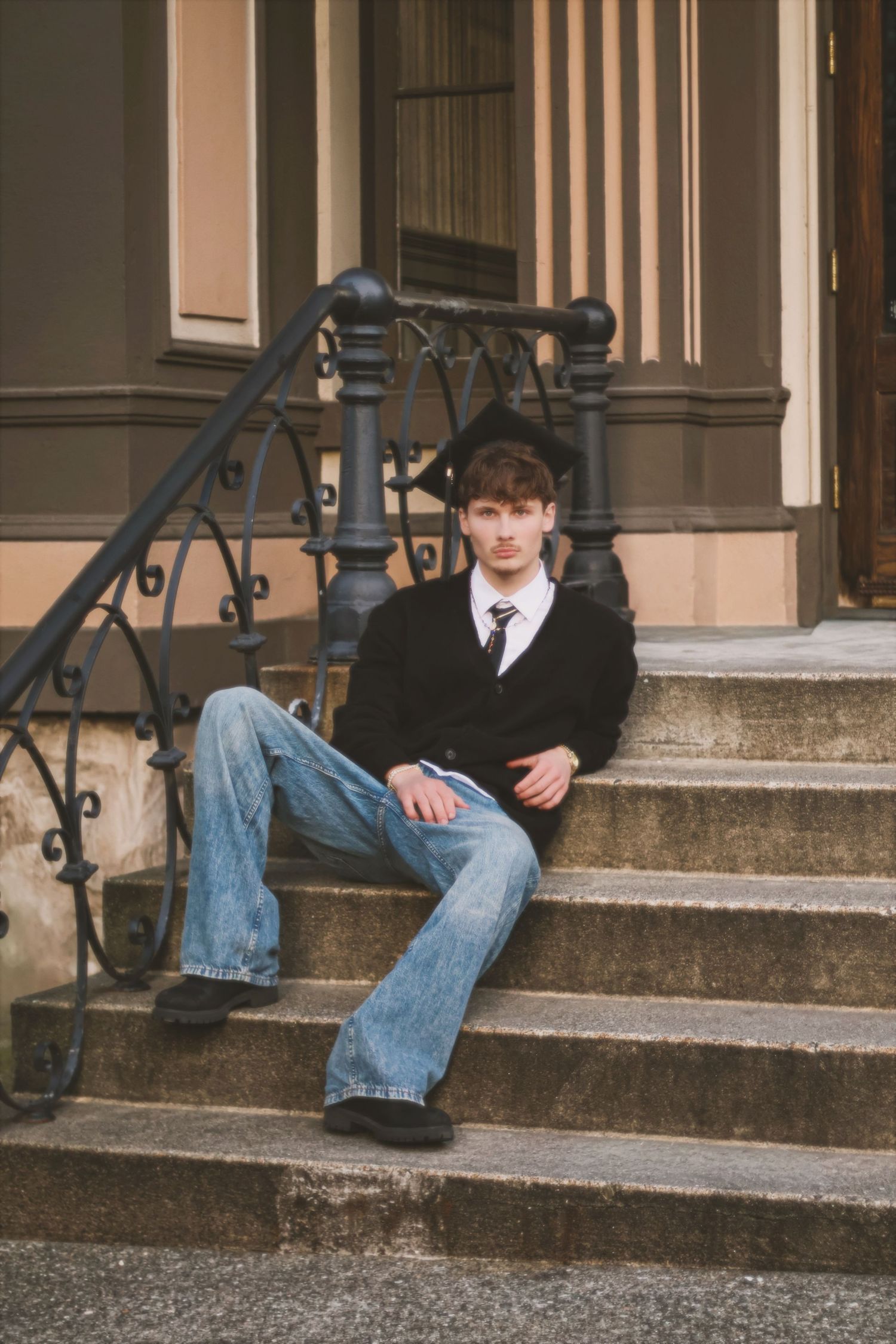 A person in a black jacket and jeans sits on concrete steps in a series of five similar poses.
