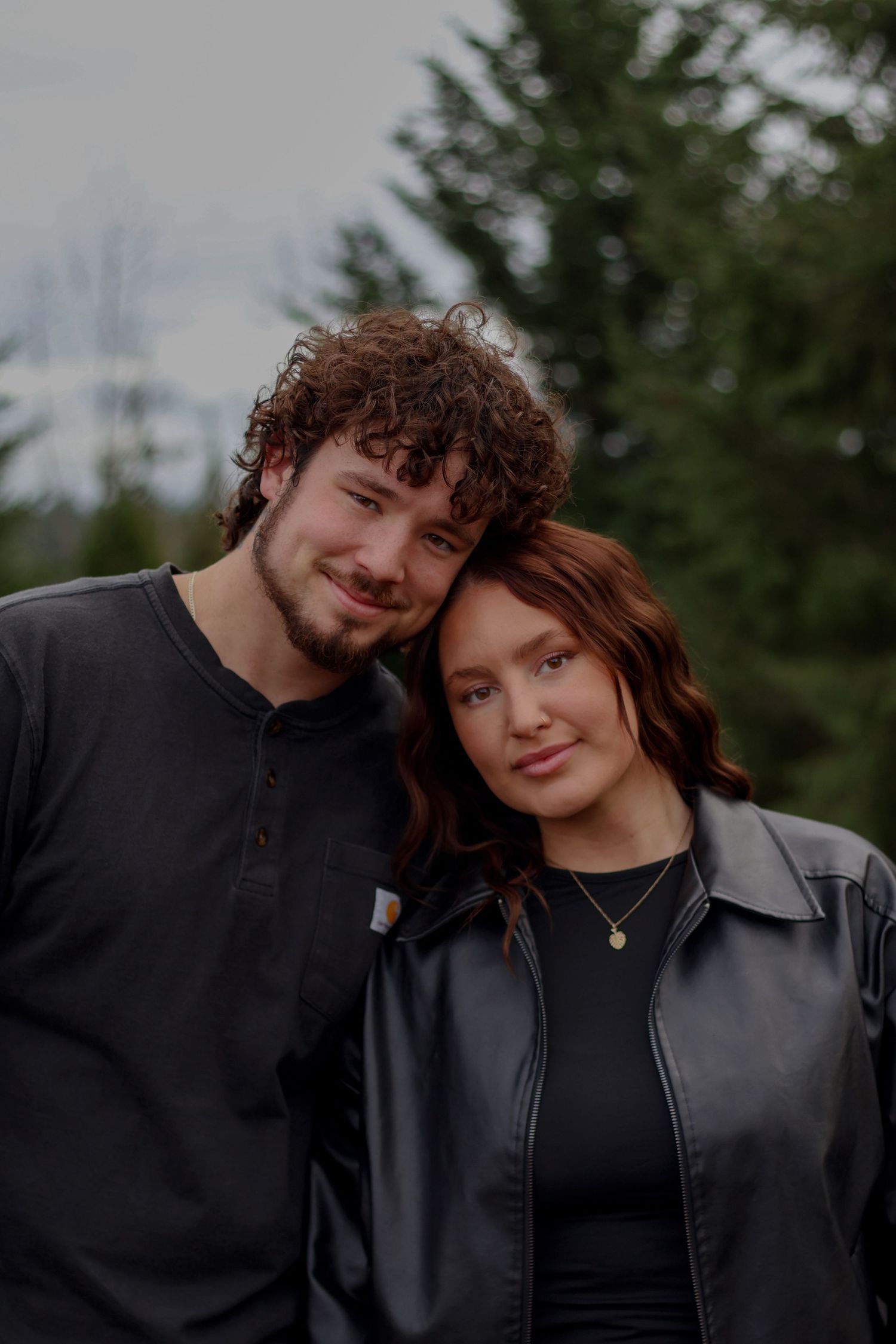 A romantic couple shares tender moments together in a series of outdoor portraits against an evergreen forest backdrop.